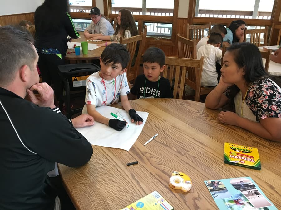 Family Camp participants talking and drawing together around a table