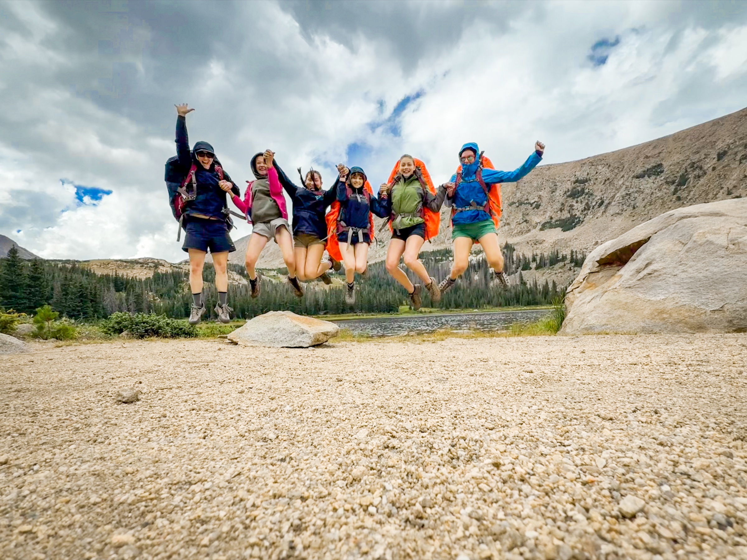 Campers jumping together in the mountains