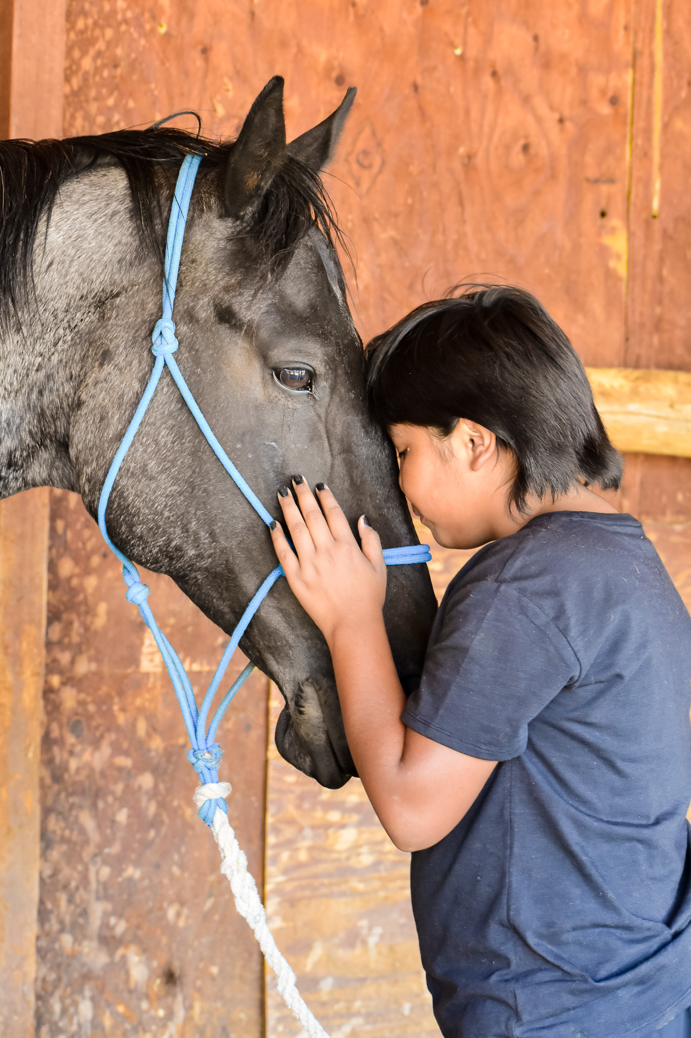 Camper resting their forehead against a horse at camp