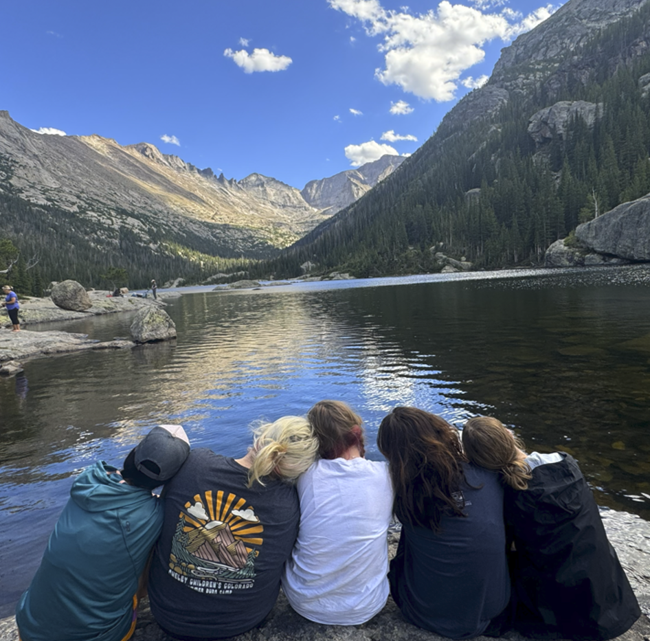 Camp participants sitting together beside a mountain lake