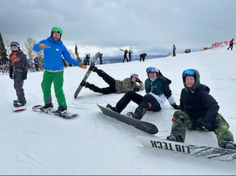 Winter Burn Camp friends posing together with their snowboards on the mountain