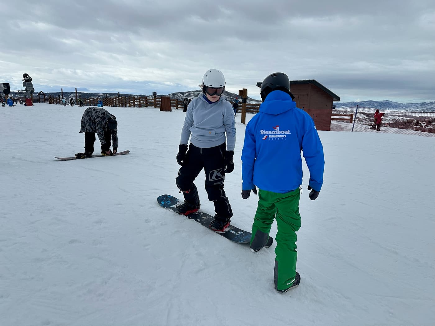 A Winter Burn Camp participant practicing on a snowboard with an instructor